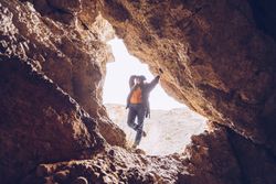 Relaxed tourist woman entering mountain cave