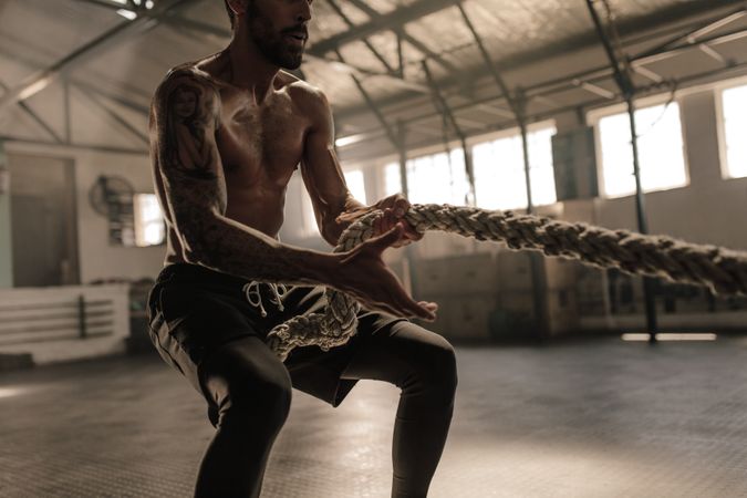 Athletic man with great physique pulling rope