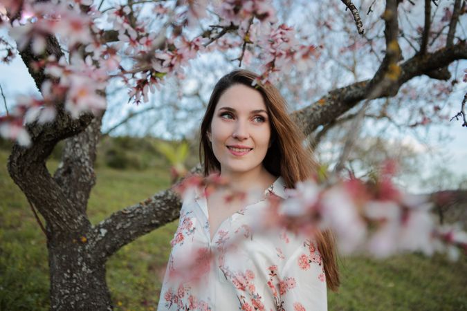 Young happy woman between trees in garden