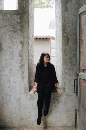 Woman sitting on concrete window