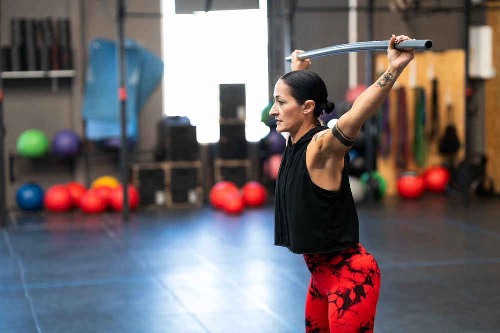 Woman warming up with a bar in a gym