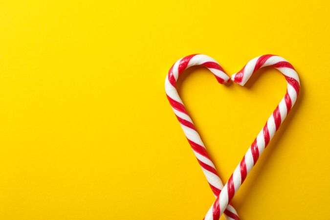 Sweet candy canes on yellow background, space for text