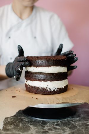 Person putting chocolate cake layers