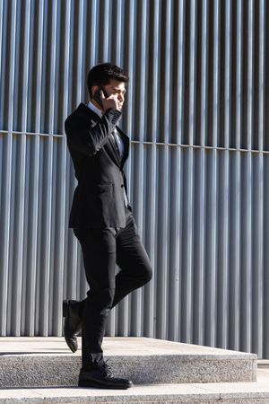 Smiling businessman speaking on smartphone in downtown