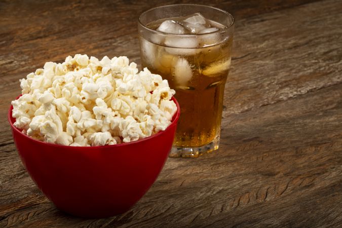 Bowl with salted popcorn and soda on the table.