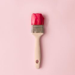 Paint brush and red tulip flower on pastel pink background
