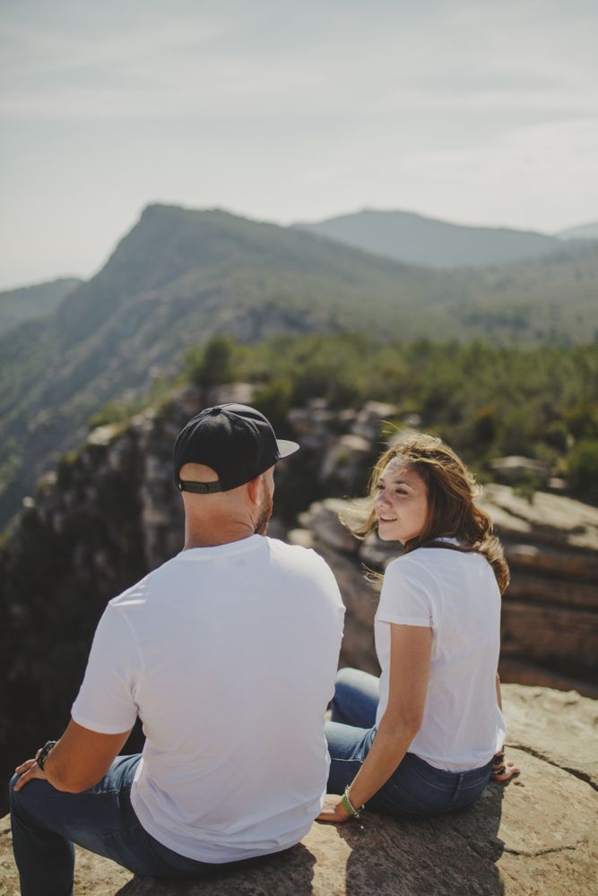 Happy couple sitting at mountain cliff