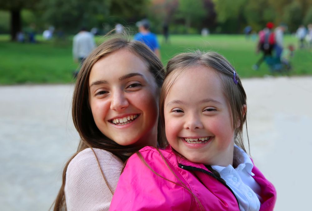 Two sisters smiling together in a public park
