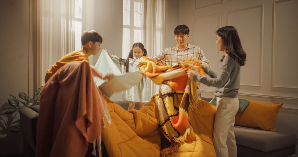 Korean Family of Four Working Together as a Team to Build a Fortress of Blankets at Home.