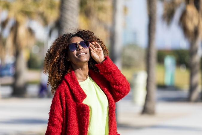 Female with head to the sun on street with palm trees
