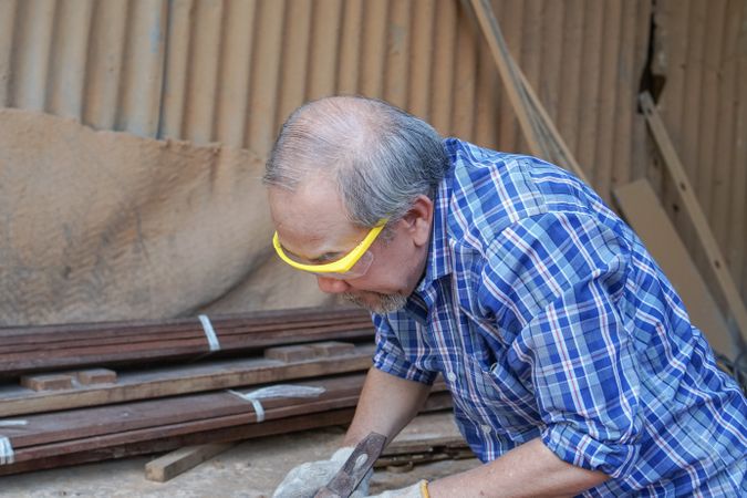 Asian carpenter working on a wooden panel in the shop
