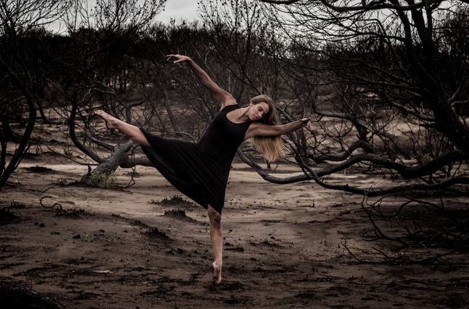 Woman dancing between dry trees