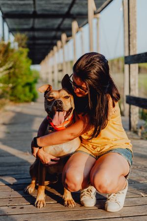 Happy adult woman hugging dog at countryside