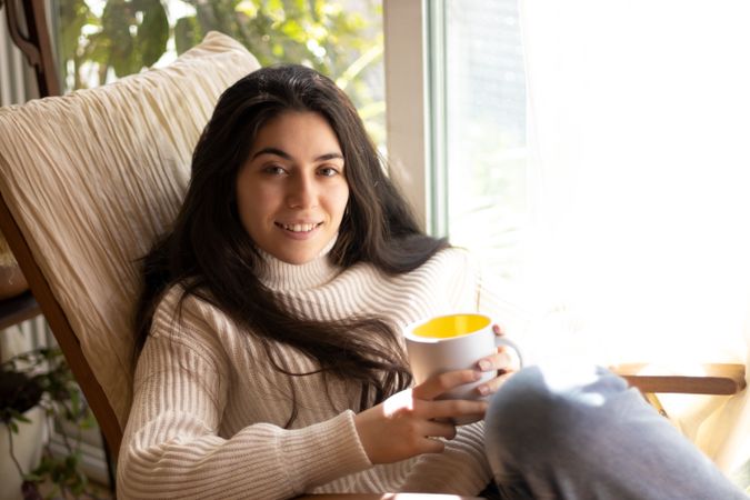 Woman sitting on a sofa with a cup of coffee.