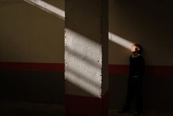 Adorable preteen boy standing near wall in sunbeam