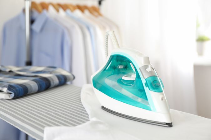 Iron and shirt on ironing board, space for text