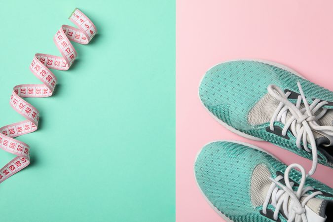 Measuring tape and sneakers on two tone background