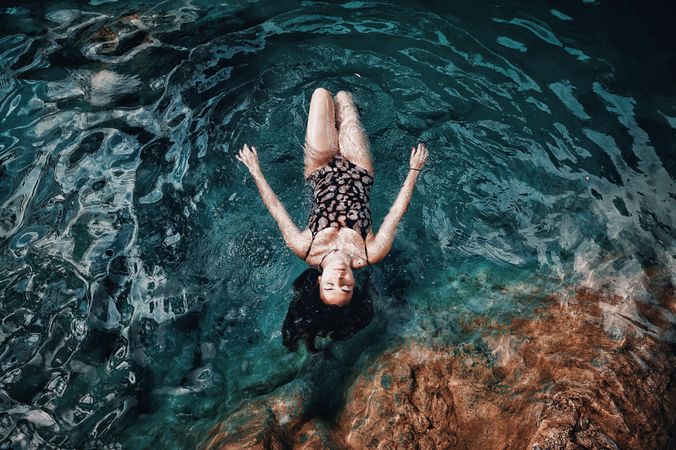 Top view of woman in floral swimsuit floats on water