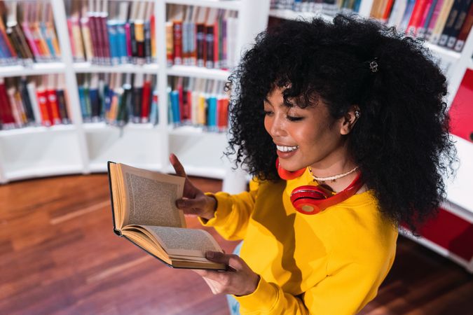 Content Black female student reading textbook in library