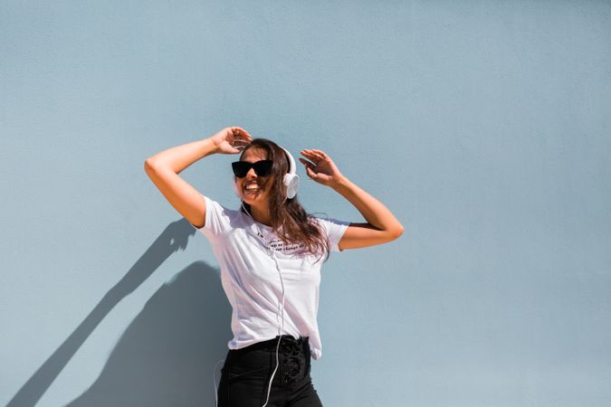 Cheerful casual woman in sunglasses standing on city street