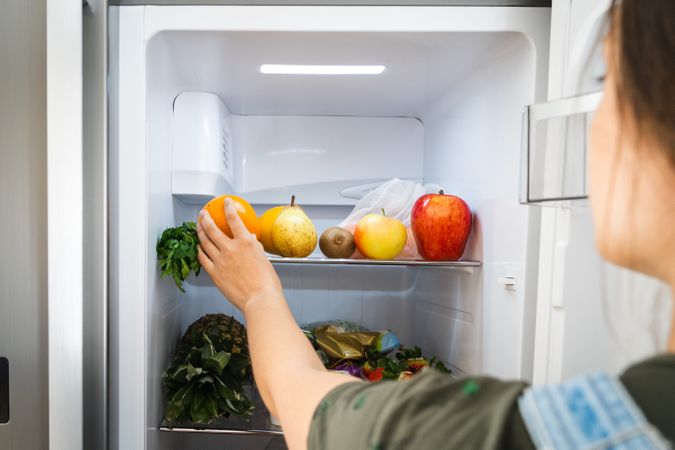 Crop woman taking fruit from fridge