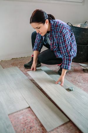 Female bricklayer placing tiles to install a floor