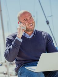 Businessman sitting with a computer in his legs and talking on the phone