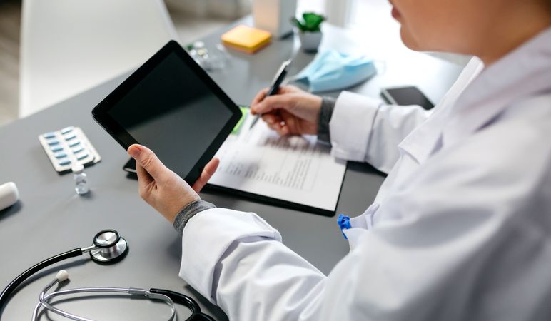 Unrecognizable female doctor using tablet while working