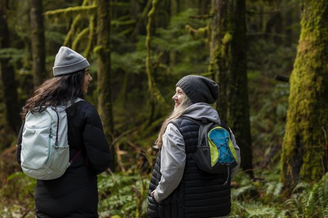 Young female and woman talking and hiking in mossy forest