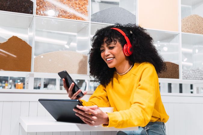 Black female using phone and enjoying music in cafe