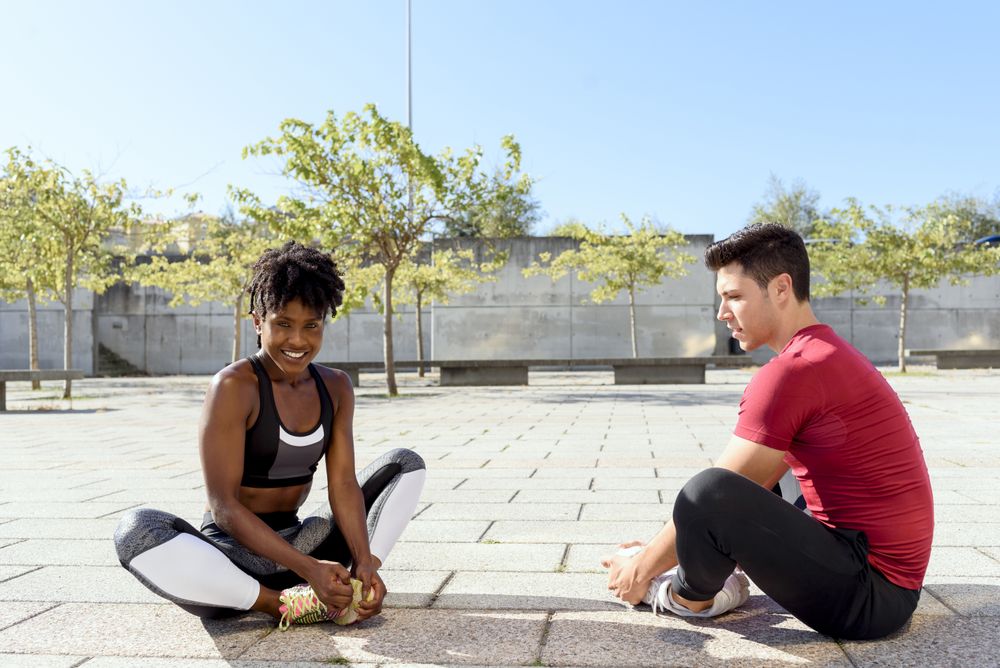 Sportive couple doing stretch exercises in city