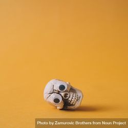 Halloween skeleton head with googly eyes and orange background lying on its side 0PMJv5