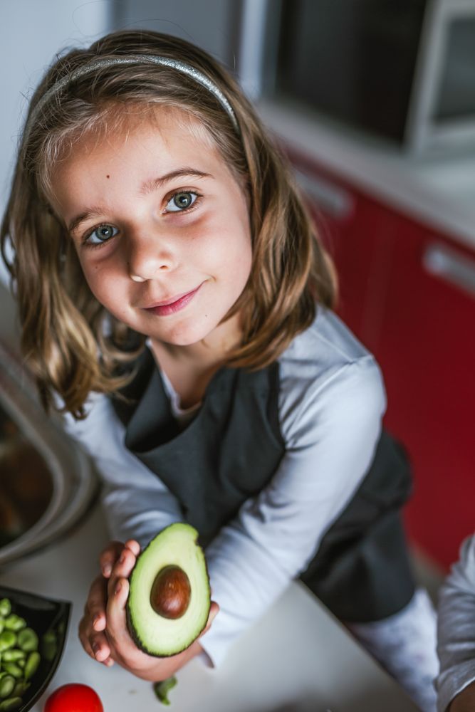 Little girl showing cut avocado