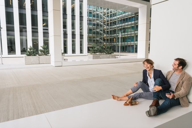 Businesspeople hugging and using smartphone on street