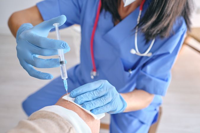 Faceless nurse in sterile gloves vaccinating patient with inject