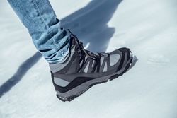 Man leg in winter boot on snow