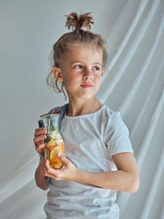 Child looking away and holding glass bottle of lemonade