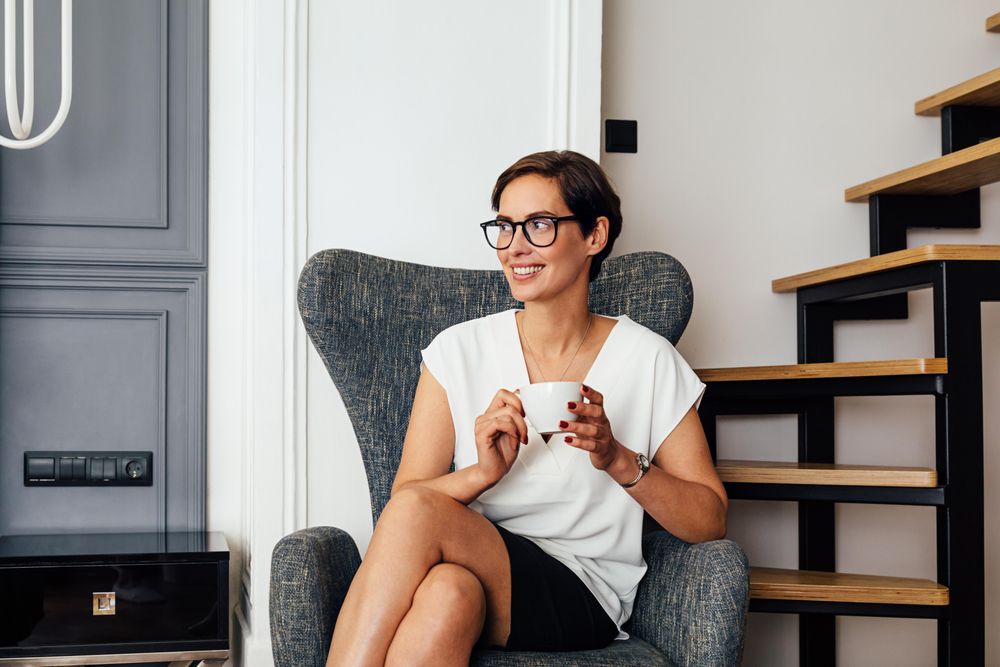 Smiling woman sitting near stairs with a coffee