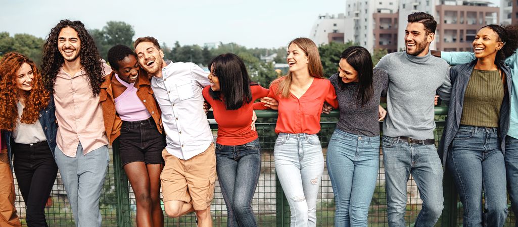 Group of multi-ethnic friends happily hugging in the park talking and joking together