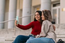 two student taking a selfie sitting on the stairs of the college