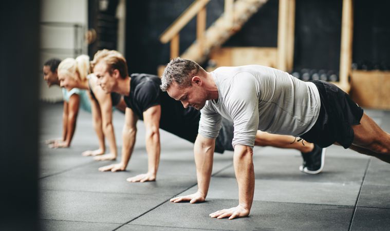 Multi-ethnic group of people in a row doing planks