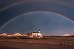 Lonely house in desert and rainbow in sky