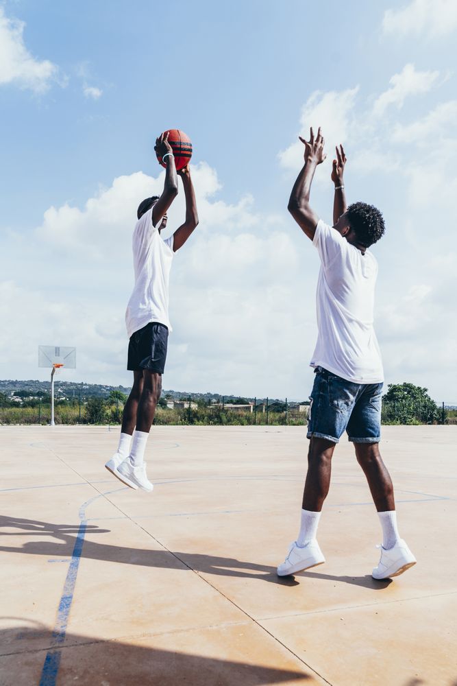 Black male friends playing basketball in bright day
