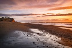 Rocks and sand on a quiet beach at sunset