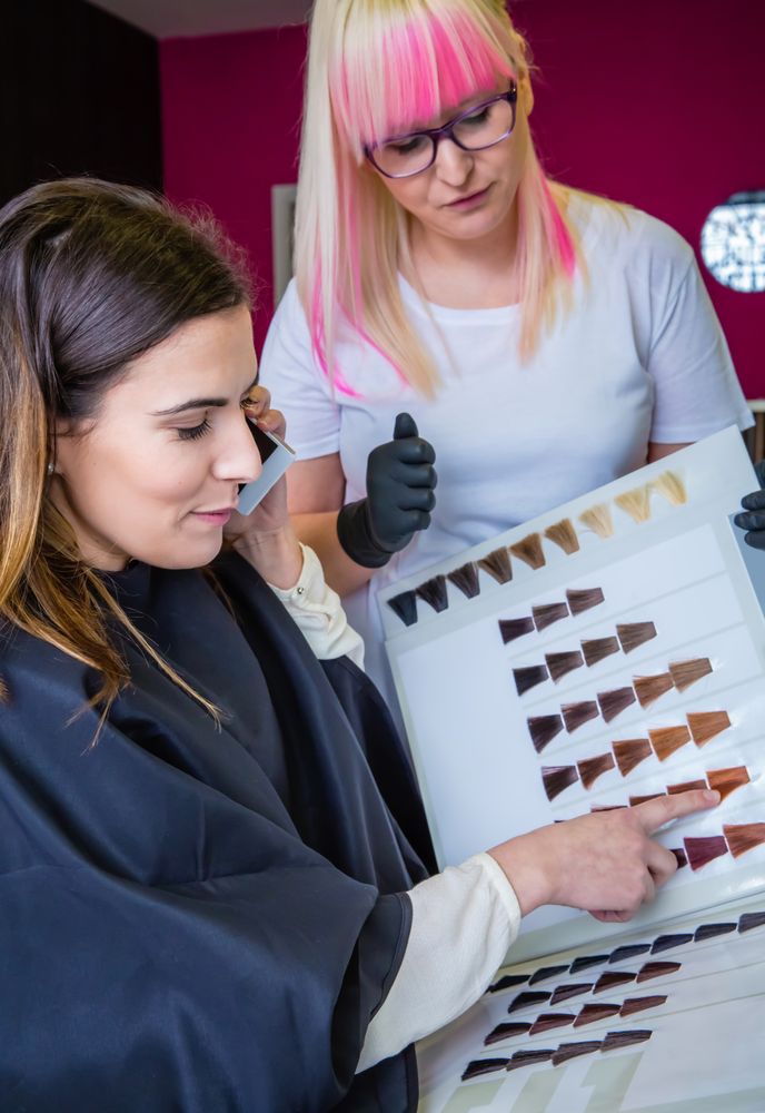 Client in salon speaking on phone while choosing hair color with stylist