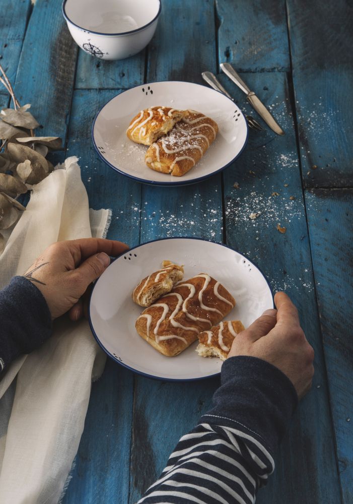 Faceless person taking sweet roll from rustic table