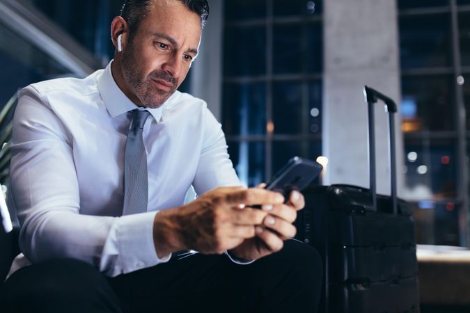 Businessman sitting at airport lounge and texting in his mobile phone