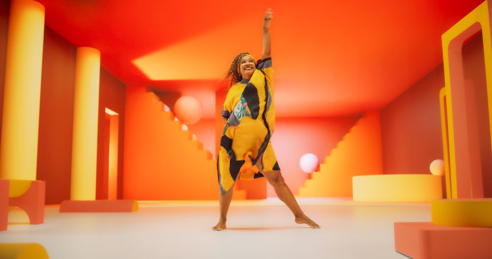 Black Woman in African Outfit Dancing Energetically in Geometric Abstract Orange Environment. Creative Female Performing Dance Choreography in Bright Studio, Making Moves, Having Fun.