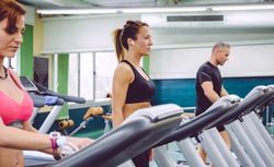 Group of people warming up on treadmills in gym
