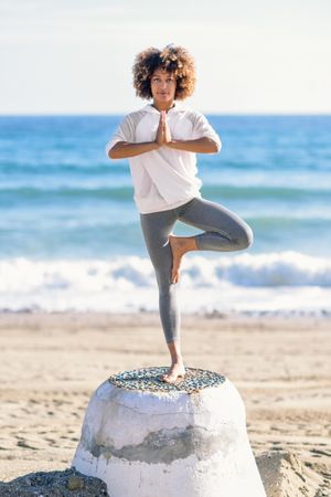 Black woman doing balance exercises on the beach